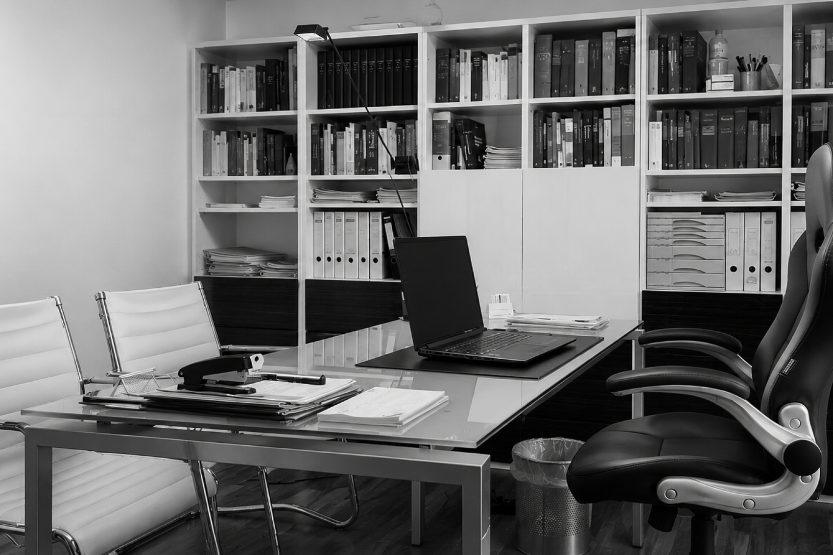 Ein professioneller Arbeitsbereich mit Schreibtisch, Laptop und vollgestopften Bücherregalen.